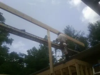 Carpenter setting a ridge beam over a new addition frame — Ice Dam Removal by Roofing Brothers in Norway
