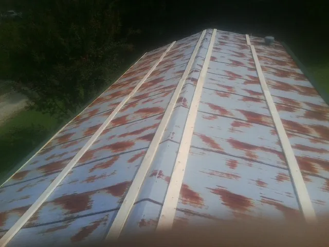 Rusted metal roof panels with new wood purlins before replacement — Storm Damage Roof Repair in Norway by Roofing Brothers